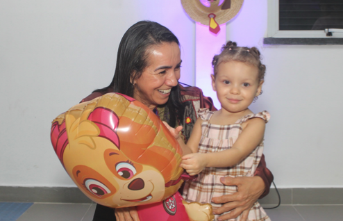 Família sorrindo com balão durante a festa Happy Bee na Roça