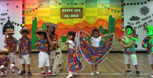 Crianças e professora em traje caipira no palco do Happy Bee na Roça