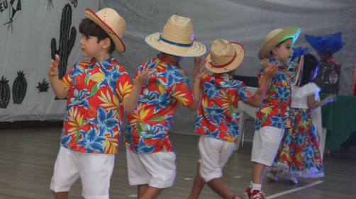 Meninos com camisas estampadas e chapéus de palha dançando