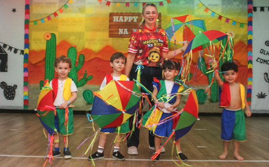 Apresentação infantil com bandeirinhas coloridas e a professora