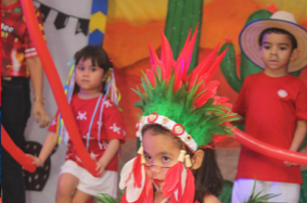 Crianças prontas para a apresentação com penachos coloridos