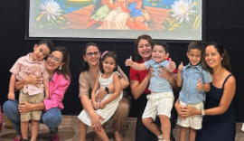 Grupo de mães e crianças reunidas em frente ao painel decorativo