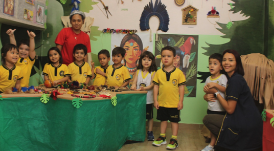 Turma do Infantil I em frente à exposição cultural do Dia dos Povos Indígenas na Happy Bee